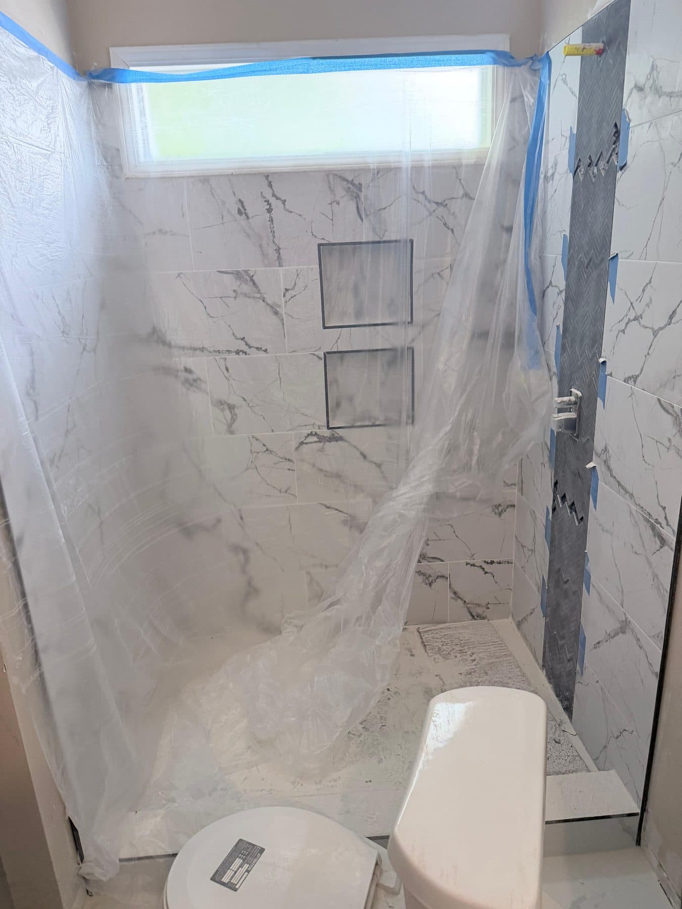 Shower glass protected with plastic sheeting during finish work